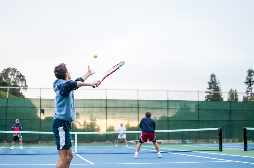 My friends playing a tennis match in the afternoon sun.